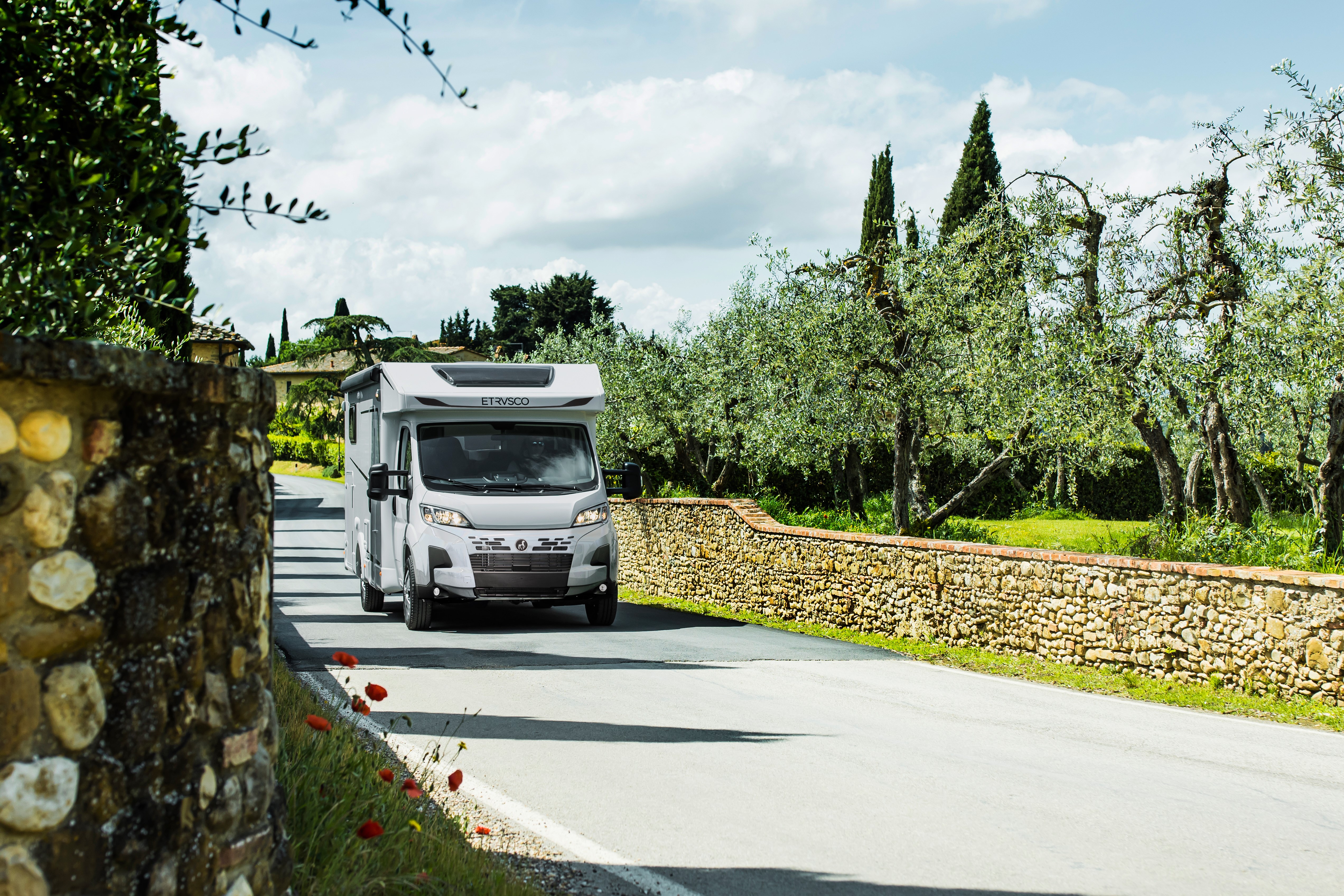 White motorhome driving through picturesque countryside scenery.