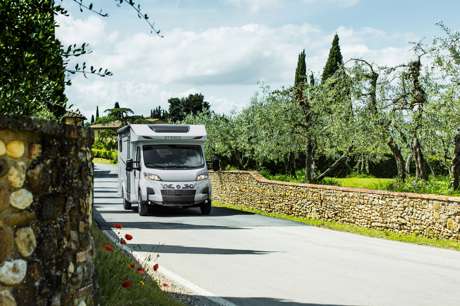 White motorhome driving through picturesque countryside scenery.