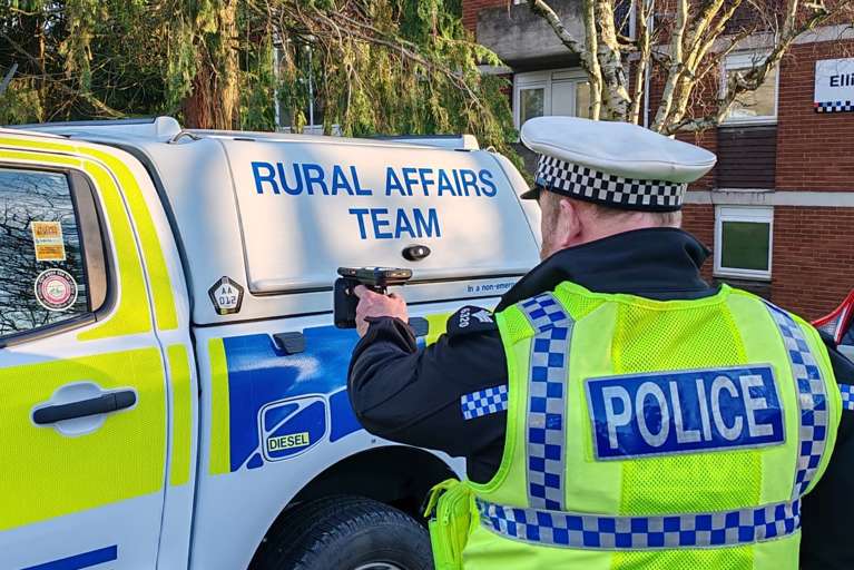 Devon & Cornwall Police officer using a handheld scanner to check vehicle identification.