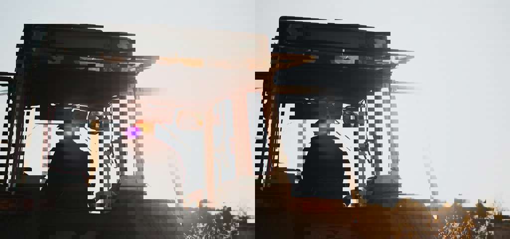 A farmer operates a tractor under clear, sunny skies.