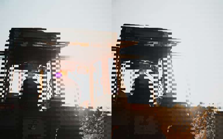 A farmer operates a tractor under clear, sunny skies.