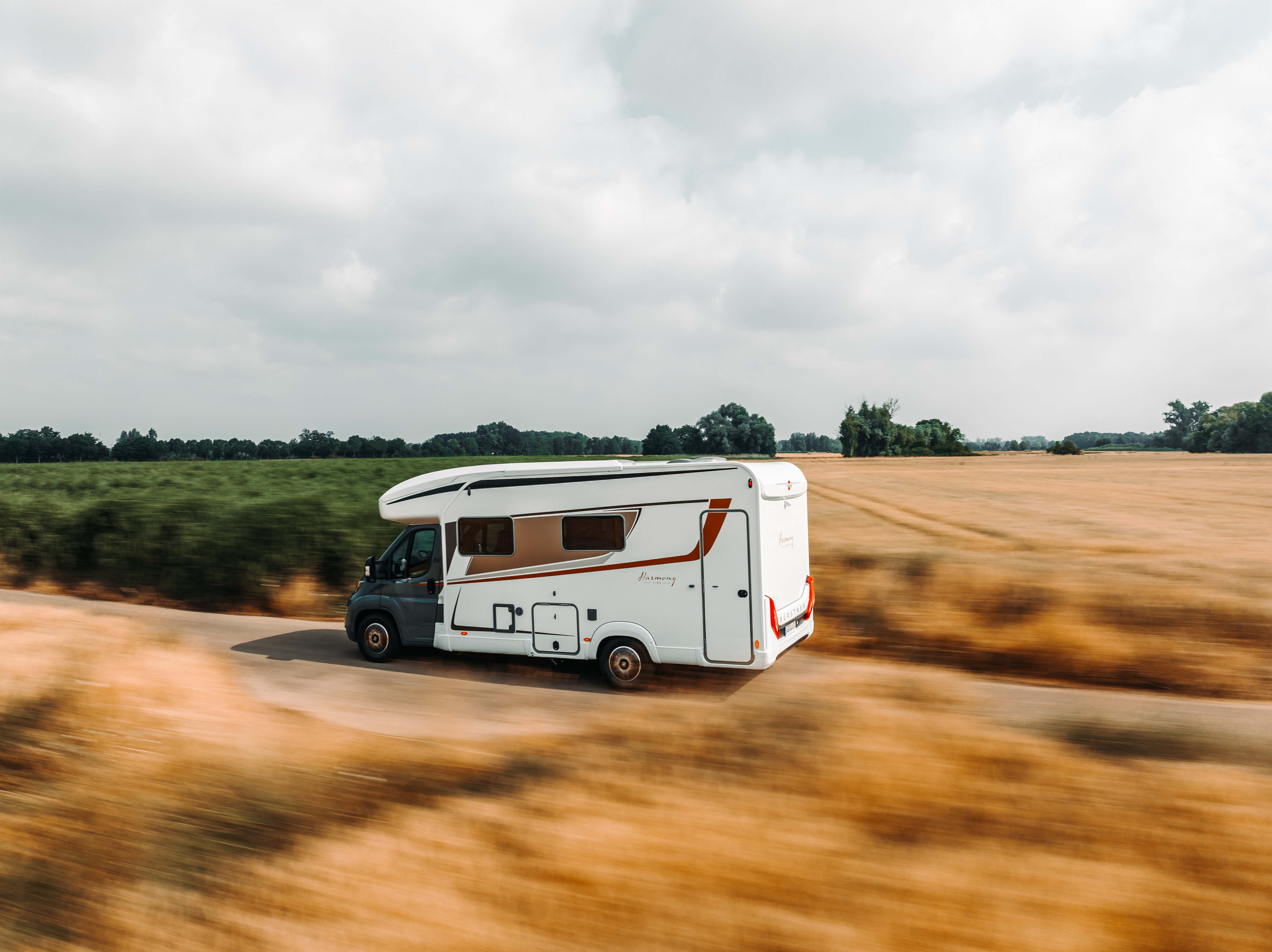 A white motorhome traveling along a scenic route in the countryside.