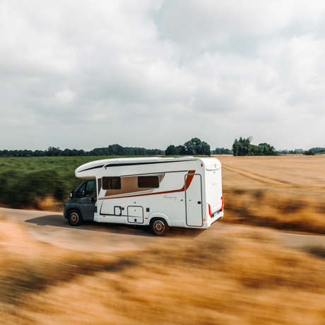 A white motorhome traveling along a scenic route in the countryside.