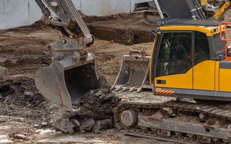 Yellow excavator actively working on a site, moving earth.