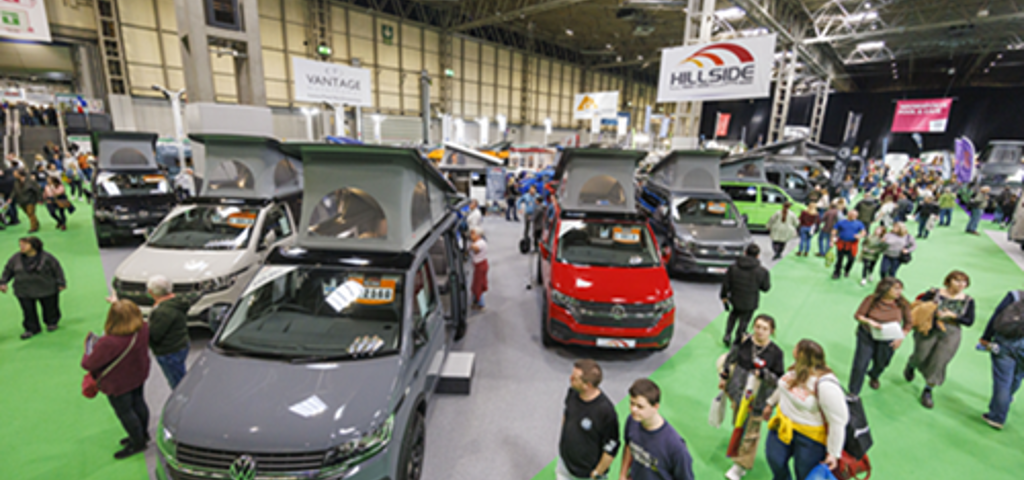 Attendees exploring the Caravan, Camping & Motorhome Show, surrounded by various campervans.