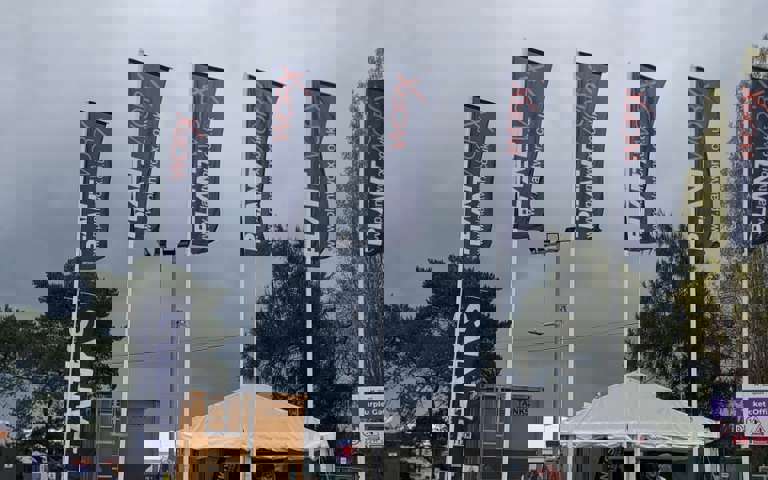 Blue PlantWorx 2025 flags at the show entrance on a cloudy day