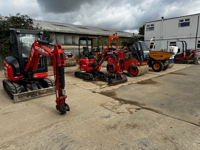 A collection of construction equipment parked side by side in a machinery yard.