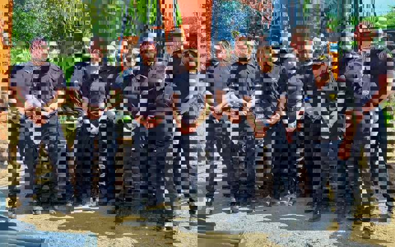 Ten Kent Police officers in blue uniforms with VIN Chip trainer, lined up in front of heavy machinery during IMI theft awareness training.