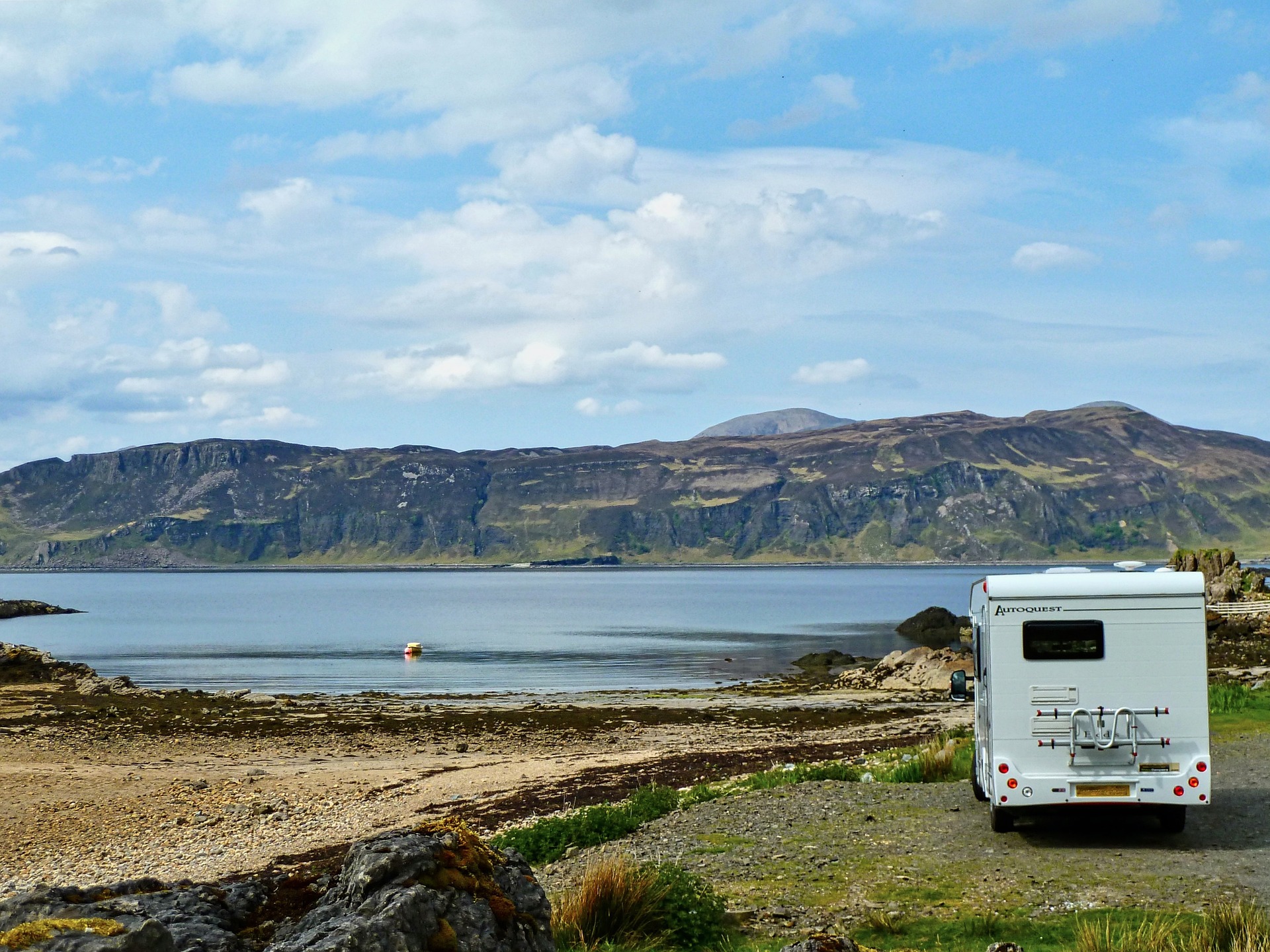 Motorhome parked beside a tranquil lake in a scenic setting.