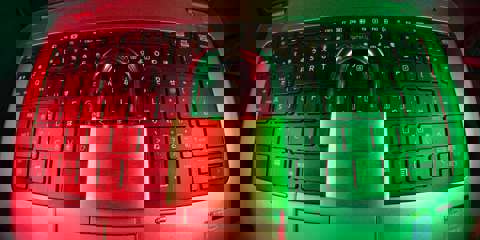 A black keyboard illuminated in pink and green light, with a padlock resting in the centre, symbolising cybersecurity.