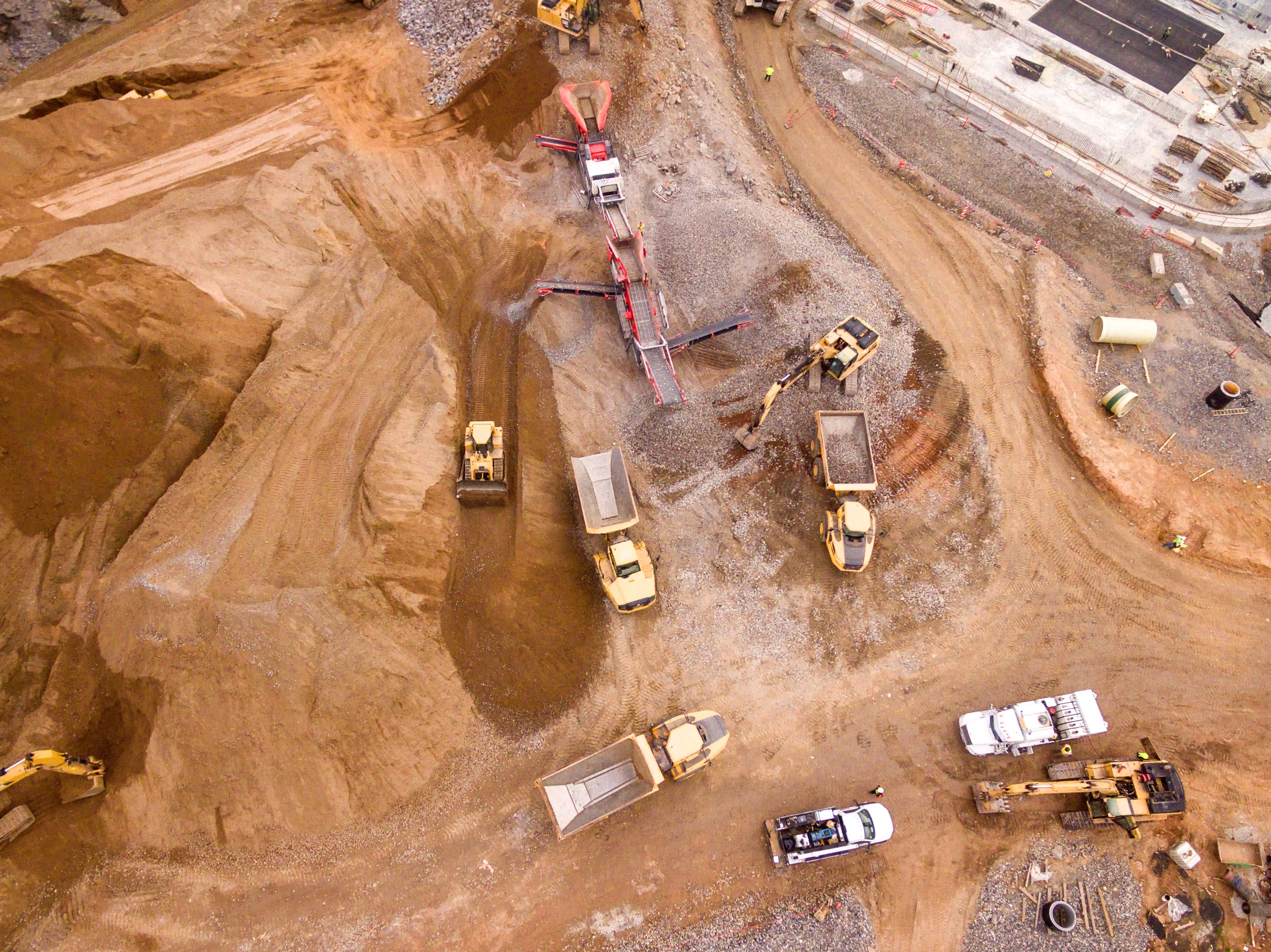 A construction site bustling with activity, featuring trucks filled with earth.