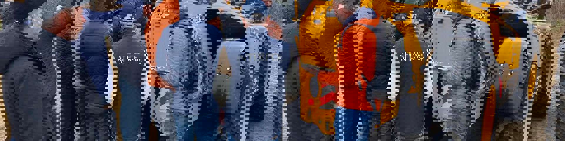 A group of students engaged in training, with JCBs and a rural landscape in the background.