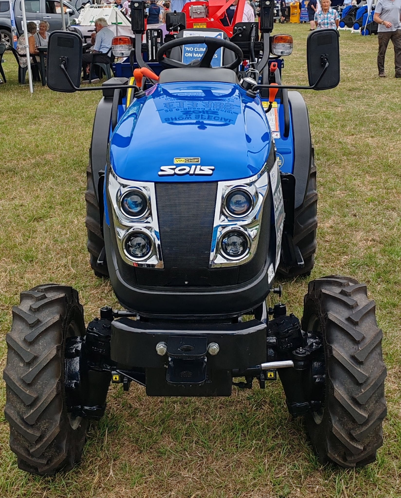 Blue Solis tractor with VIN Chip security marking on the front bonnet, displayed on a showground.