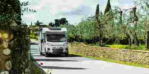 White motorhome driving through picturesque countryside scenery.