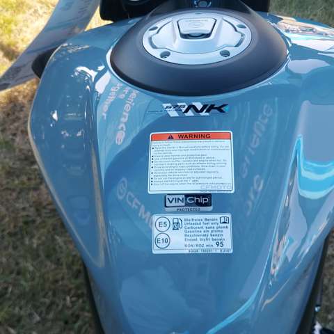 Close-up of a light blue CFMOTO motorcycle fuel tank featuring a VIN Chip domed resin warning label to indicate security protection.