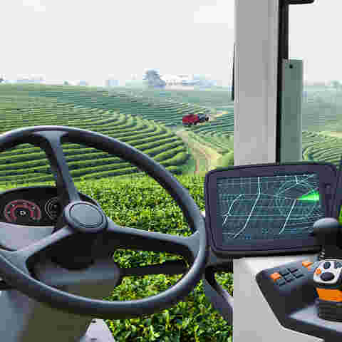 A GPS navigation screen in the cab of a tractor positioned in lush green fields.