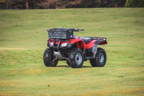 Red quad bike parked in a green field.